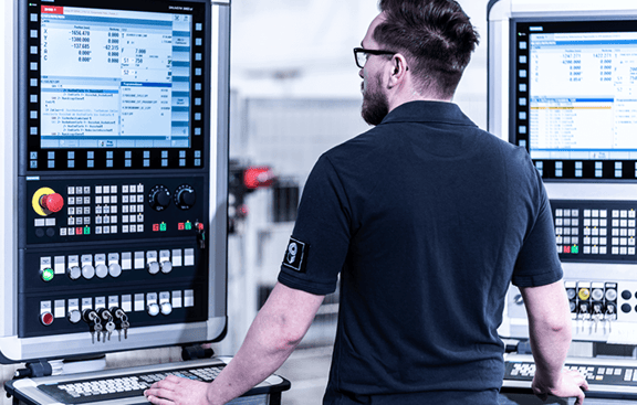 REITZ-Mitarbeiter bedient CNC-Steuerung mit mehreren Monitoren 