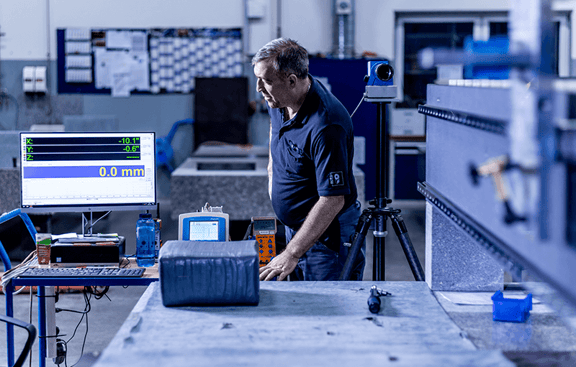 Mitarbeiter von REITZ Natursteintechnik prüft die Präzision eines überarbeiteten Granit-Werkstücks mithilfe elektronischer Messsysteme und Auswertungssoftware.