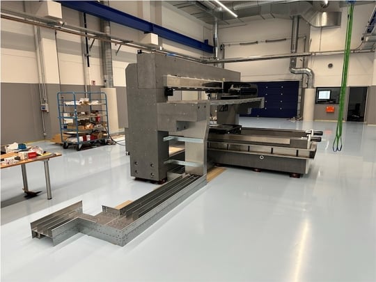 Motion system with visible cable routing and linear axes on granite structure - Machine installation in production hall