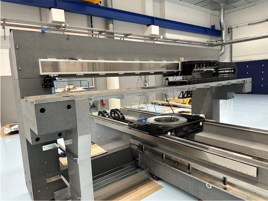 Detailed view of a motion system with mounted rotation axis on granite platform - visible linear drives and cable routing