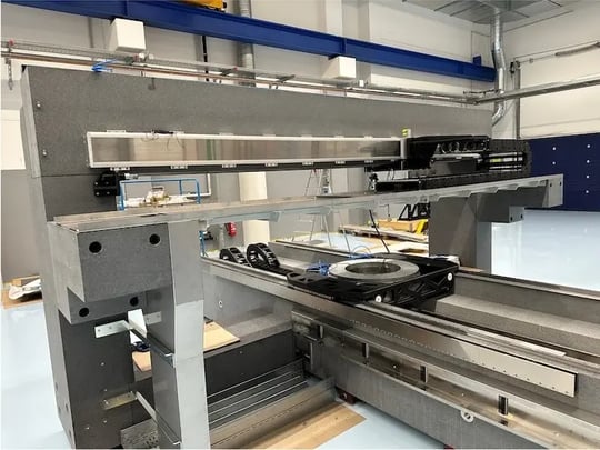 Detailansicht eines Motion-Systems mit montierter Rotationsachse auf Granitplattform – sichtbare Linearantriebe und Kabelführung