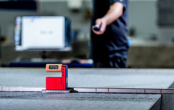 Präzise Messdienstleistung bei REITZ Natursteintechnik: elektronische Messung auf Granit-Komponente zur Qualitätssicherung und Genauigkeitsprüfung.
